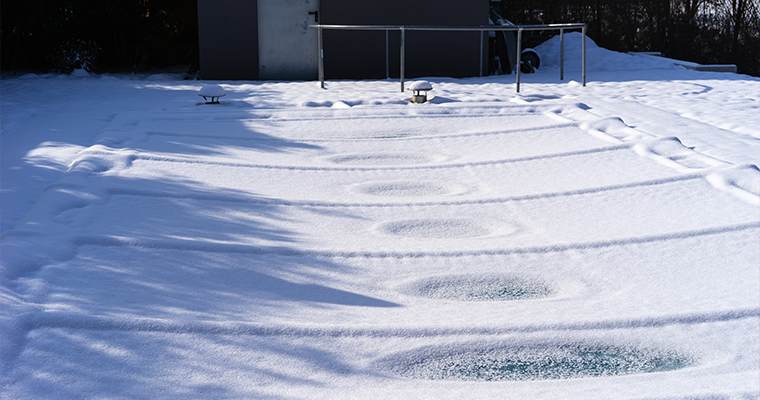 Mit Schnee bedeckte Poolplane als Winterabdeckung